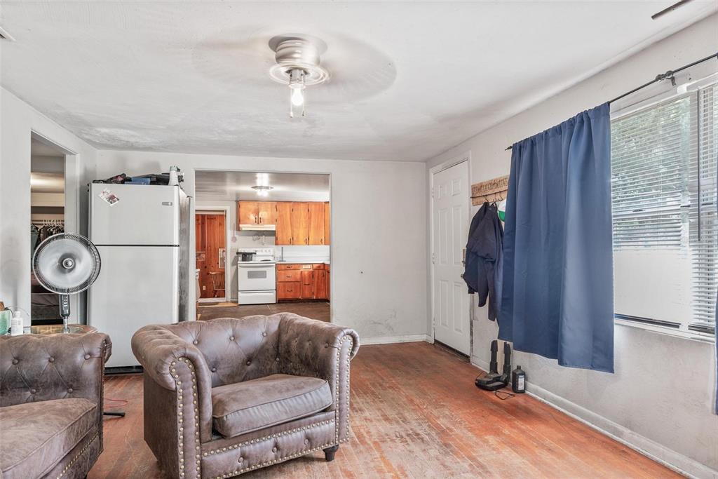 A living room with hardwood floors, a tufted armchair, and a view into the kitchen — 4849 GRAND AVENUE, DE LEON SPRINGS, FL