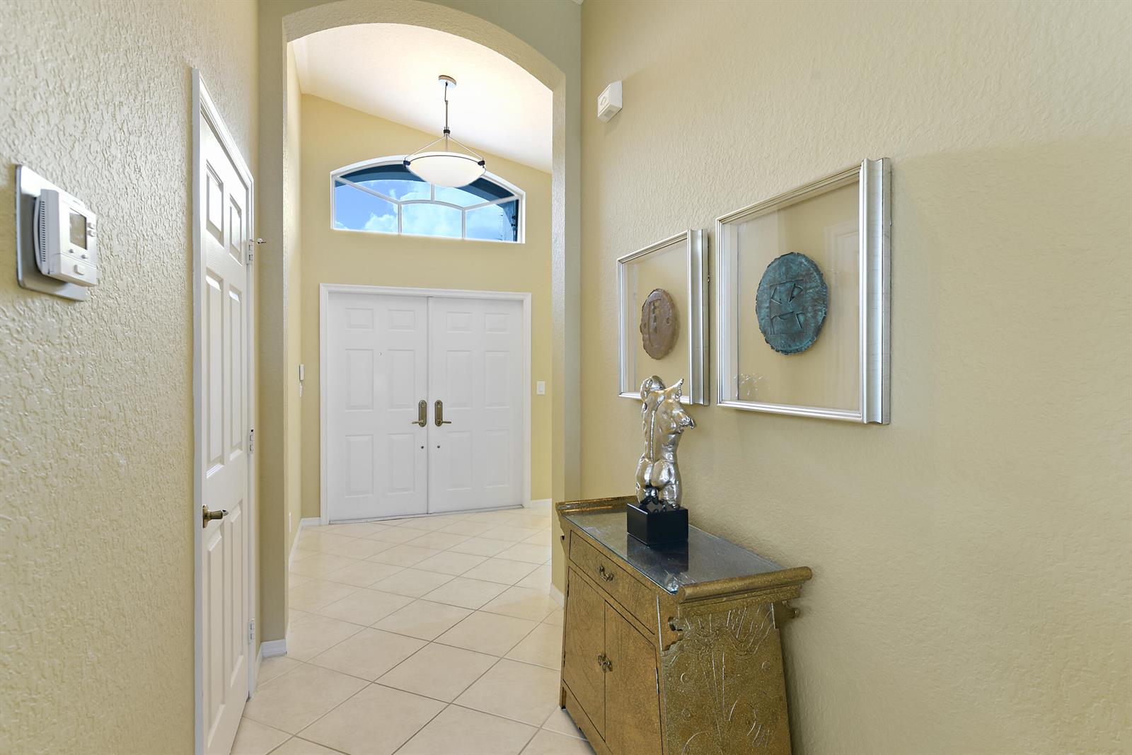 An entryway features a tiled floor, a gold console table, and a double-door front entrance — 7118 Treviso Lane, Boynton Beach FL 33472, BOYNTON BEACH, FL