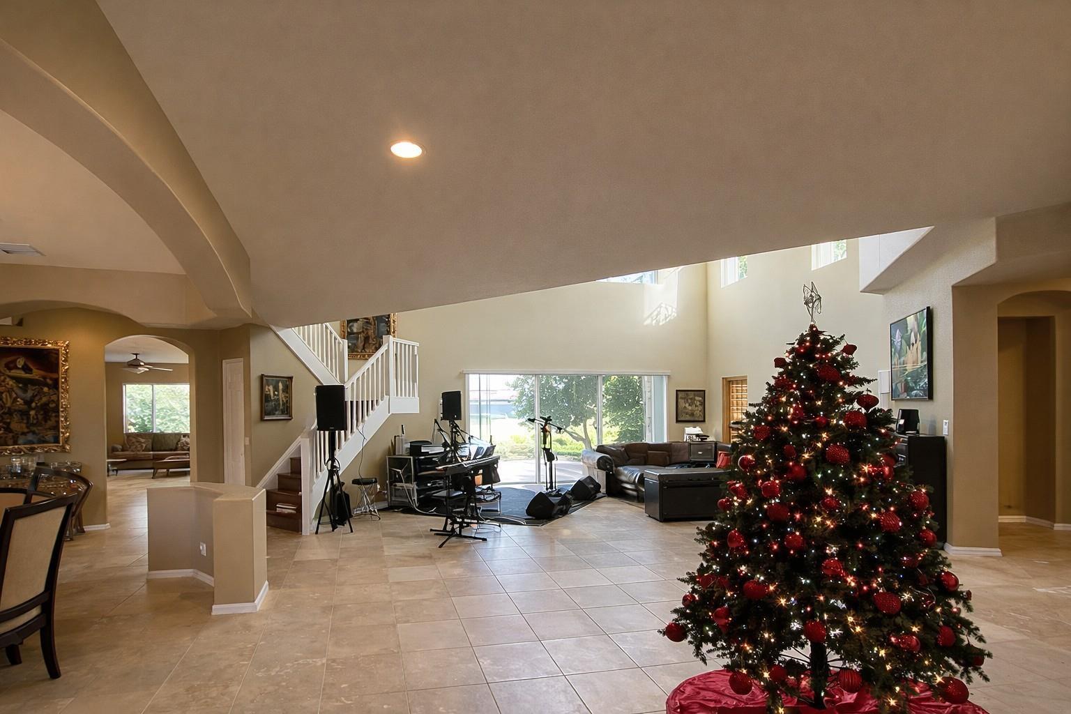 A spacious living room features tile flooring, a Christmas tree, and a musical performance area — 1381 Beacon Circle, Wellington FL 33414, WELLINGTON, FL