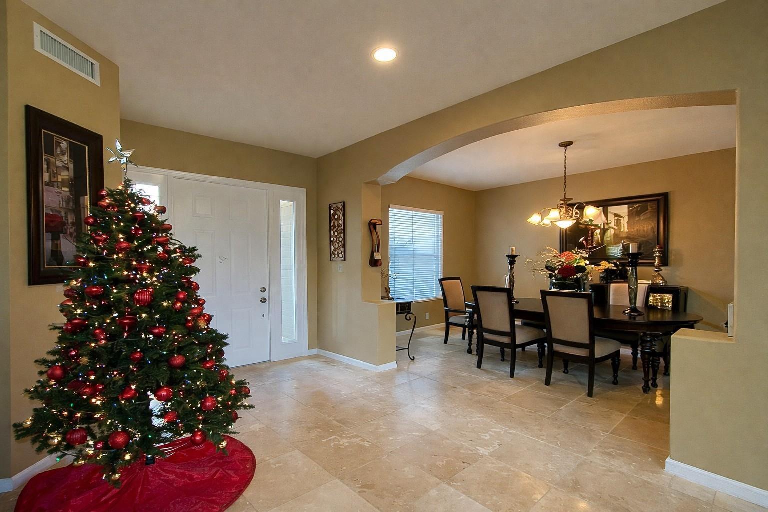 A tiled entryway with a Christmas tree leads into a formal dining room with arched walls — 1381 Beacon Circle, Wellington FL 33414, WELLINGTON, FL