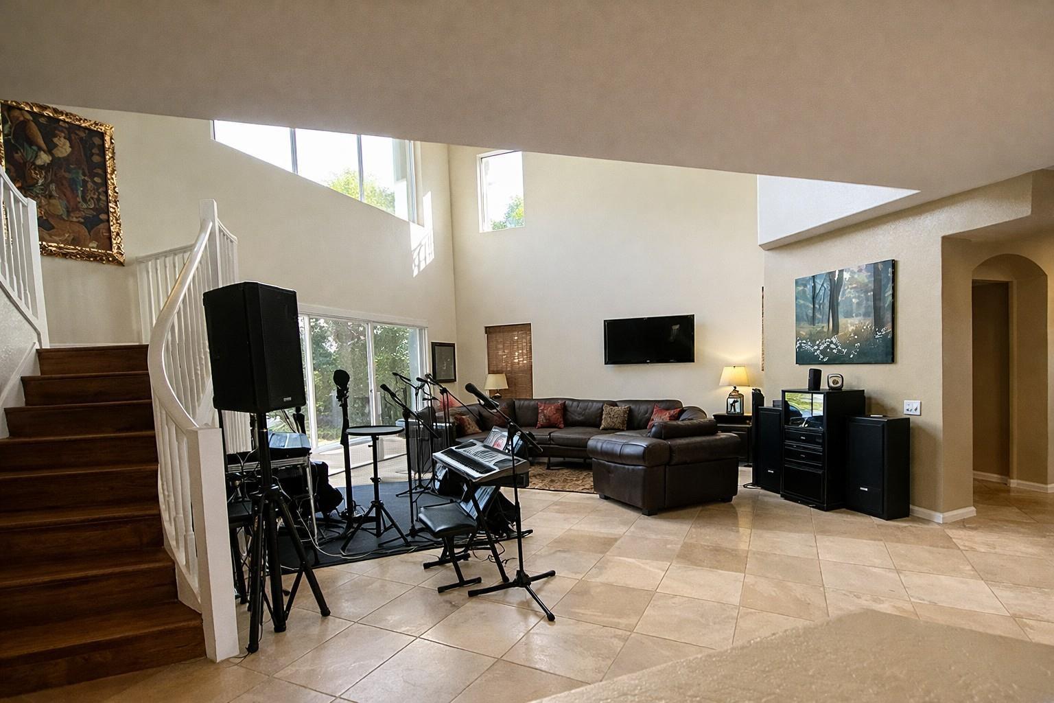 A spacious living room features tile flooring, a staircase, and a musical setup with speakers — 1381 Beacon Circle, Wellington FL 33414, WELLINGTON, FL