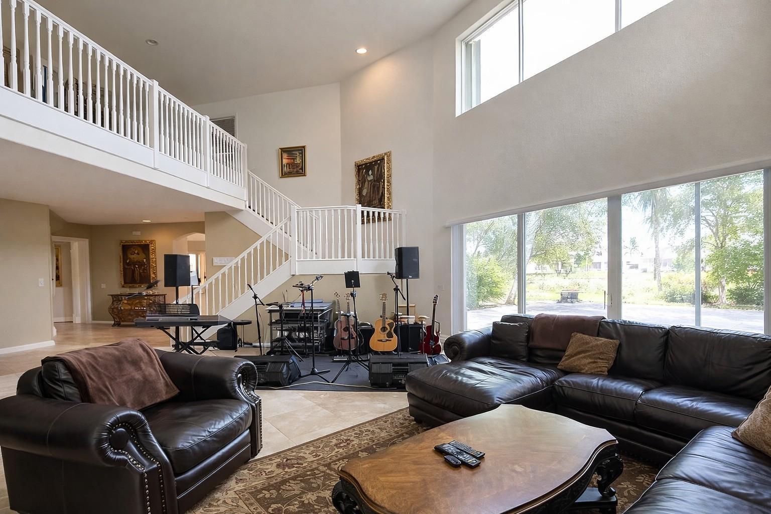 A spacious living room features a lofted staircase, musical instruments, and large floor-to-ceiling windows — 1381 Beacon Circle, Wellington FL 33414, WELLINGTON, FL