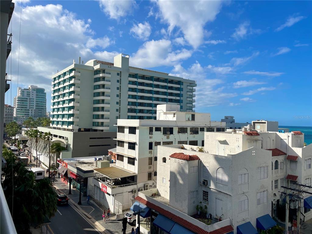 An elevated view shows a street scene with multi-story buildings and a glimpse of the ocean — 1124 ASHFORD AVENUE UNIT 6A, SAN JUAN, PR