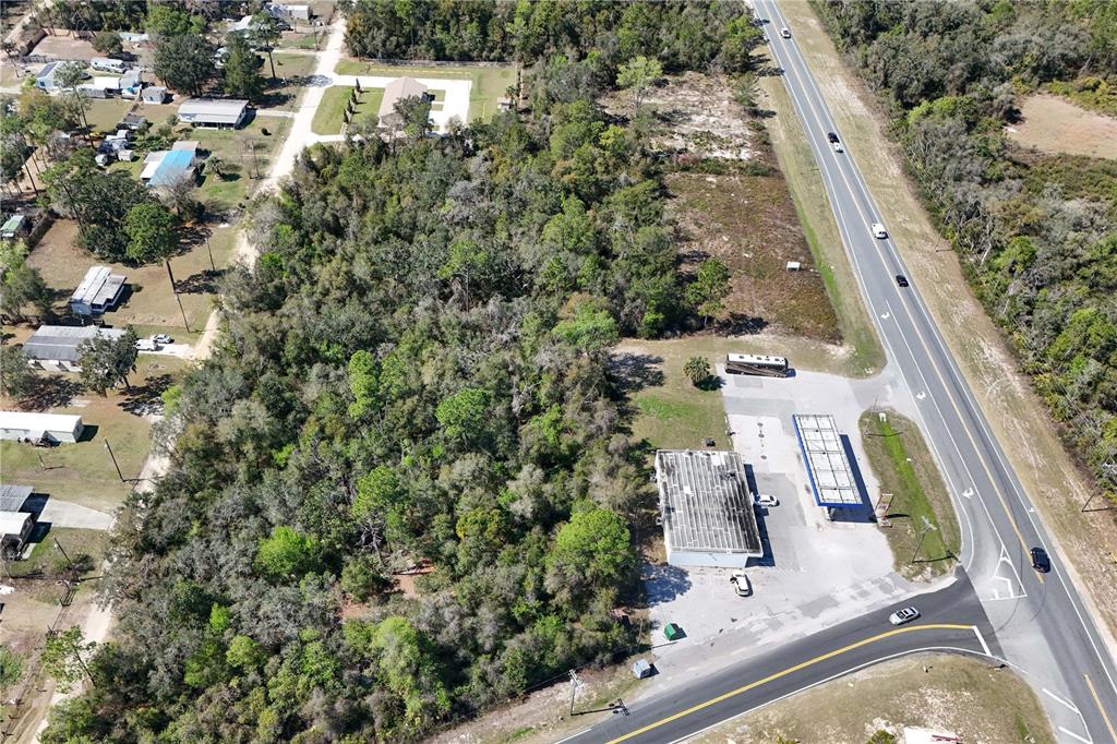 An aerial view shows a commercial gas station property adjacent to a large wooded lot — 18000 E HWY 40, SILVER SPRINGS, FL