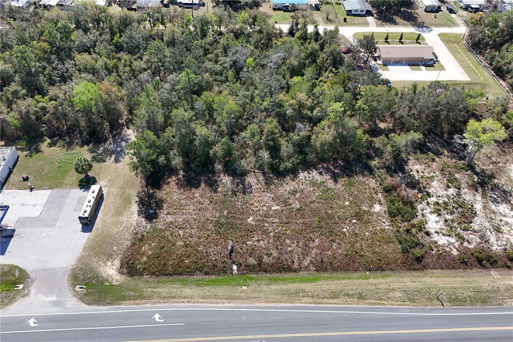 An aerial view shows a vacant, rectangular lot bordered by a road, trees, and buildings — 18000 E HWY 40, SILVER SPRINGS, FL
