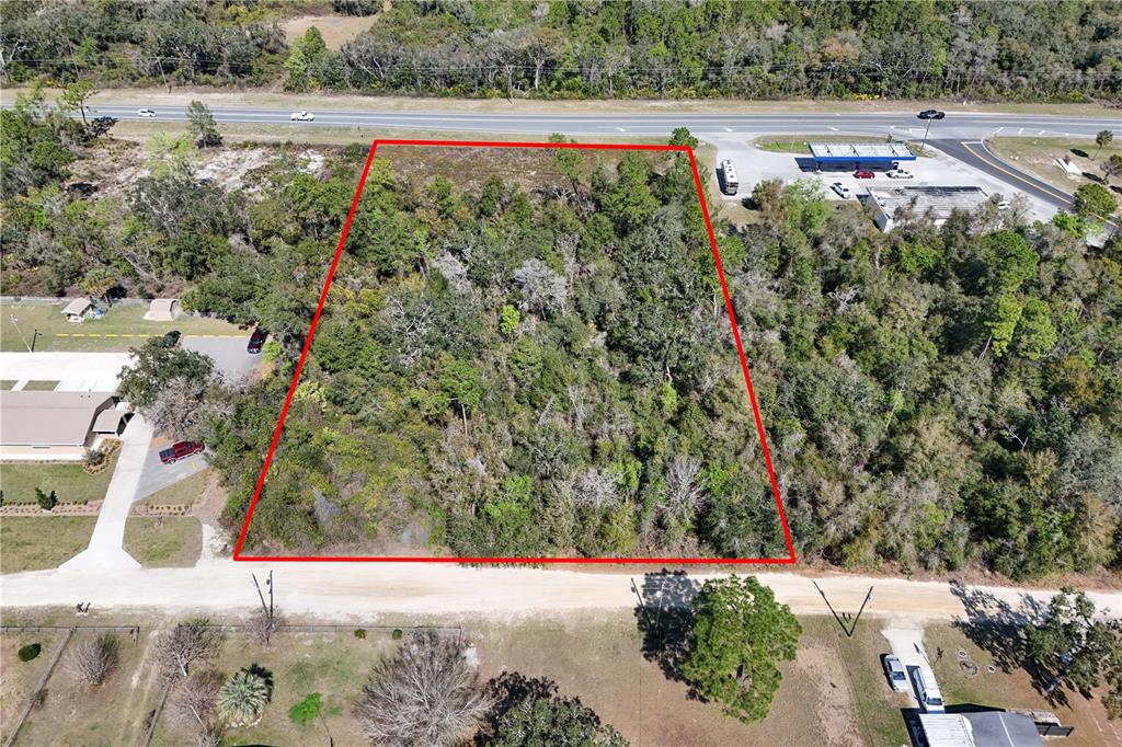 An aerial view shows a rectangular, wooded vacant lot outlined in red near a highway — 18000 E HWY 40, SILVER SPRINGS, FL