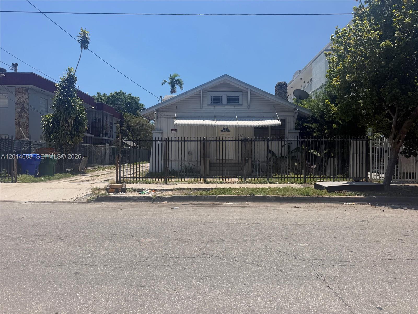 A single-story house with a white facade and metal fence sits behind a paved street — 1236 NW 5th St, Miami FL 33125, MIAMI, FL
