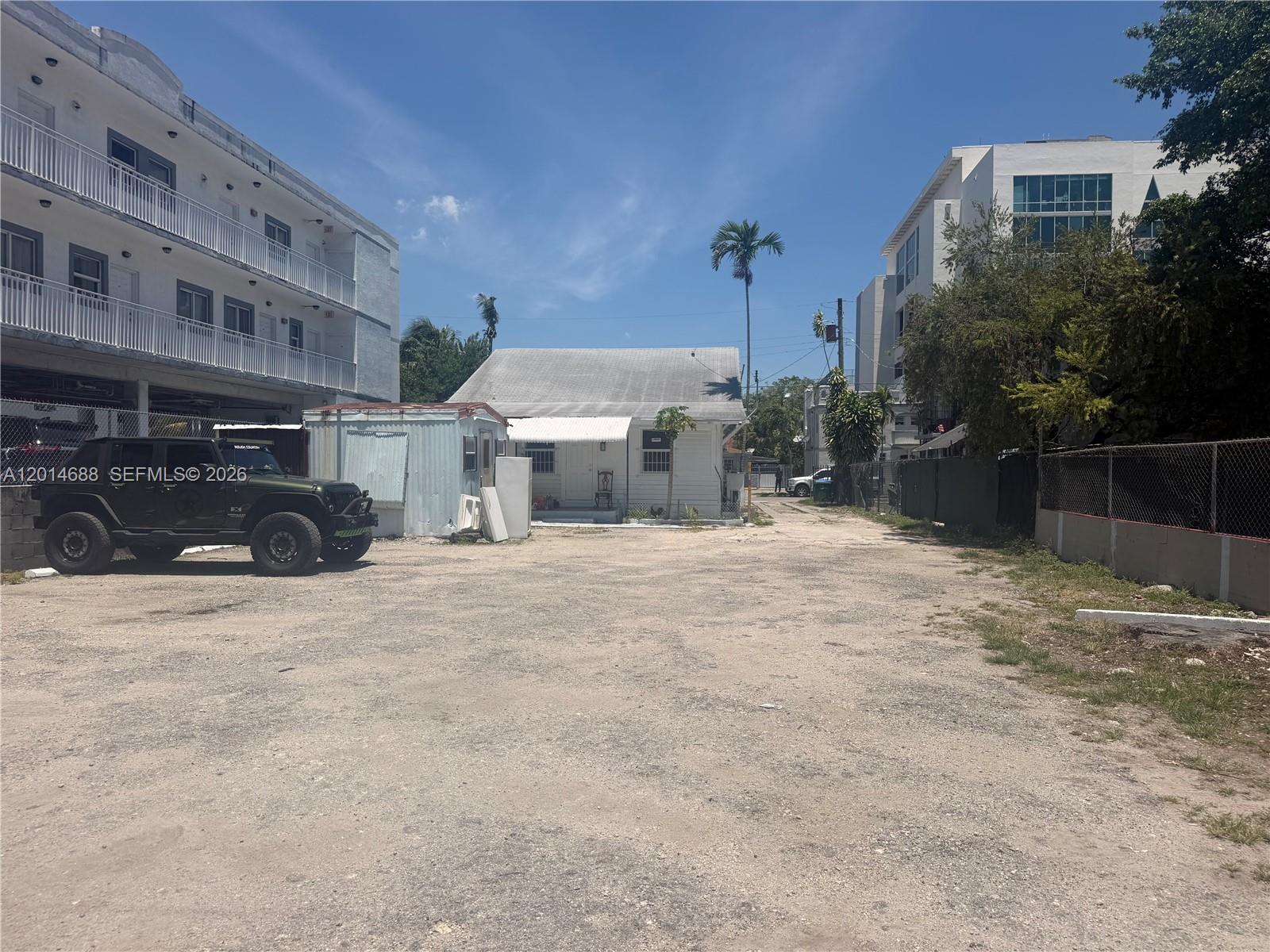 A gravel lot sits between a white apartment building and a small house — 1236 NW 5th St, Miami FL 33125, MIAMI, FL