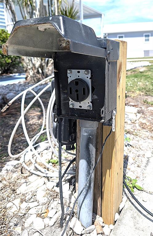 An outdoor electrical outlet box mounted on a wooden post in a rocky yard — 3333 26TH AVENUE E UNIT 1335, BRADENTON, FL