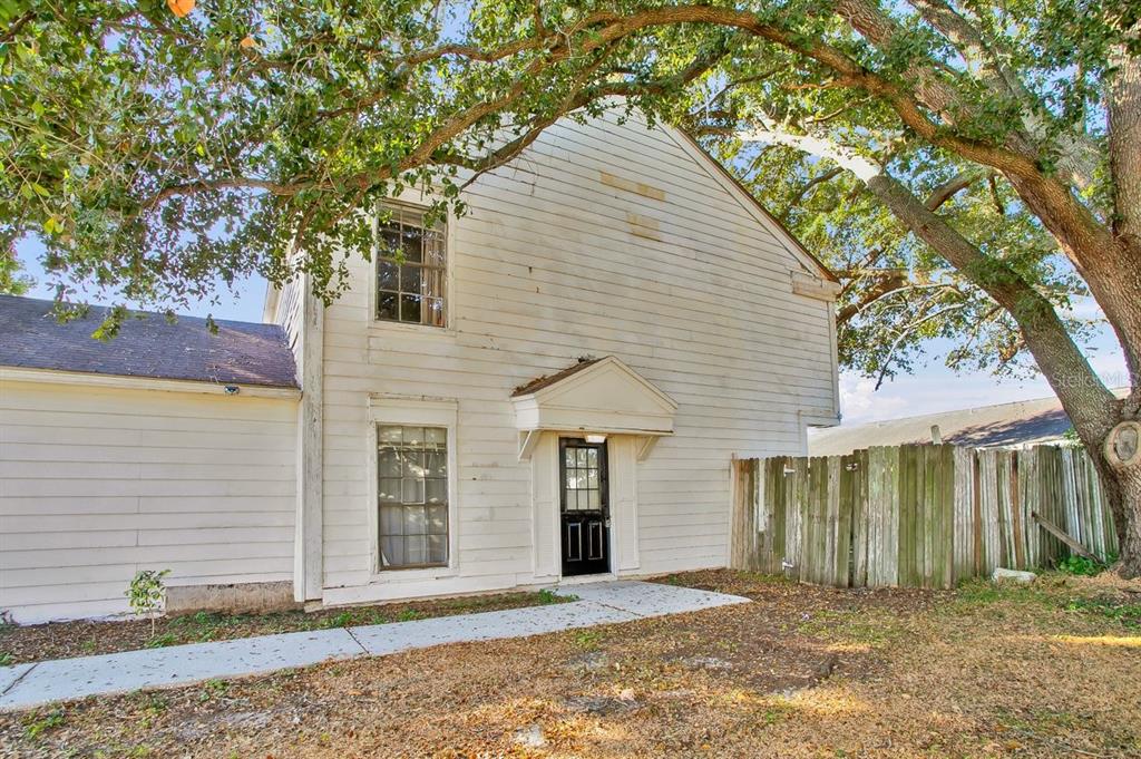 A two-story house exterior with white horizontal siding, a black front door, and large trees — 1817 CRYSTAL GROVE DRIVE, LAKELAND, FL