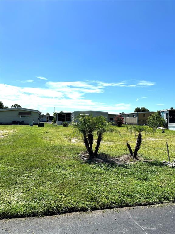 A grassy lot with two small palm trees sits in front of several mobile homes — 239 ESTRADA, NORTH PORT, FL