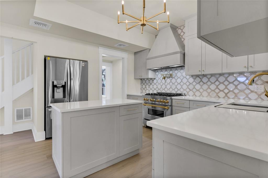 A modern kitchen features gray cabinets, white quartz countertops, a stainless steel range, and island — 226 N ELLIOTT AVENUE, SANFORD, FL