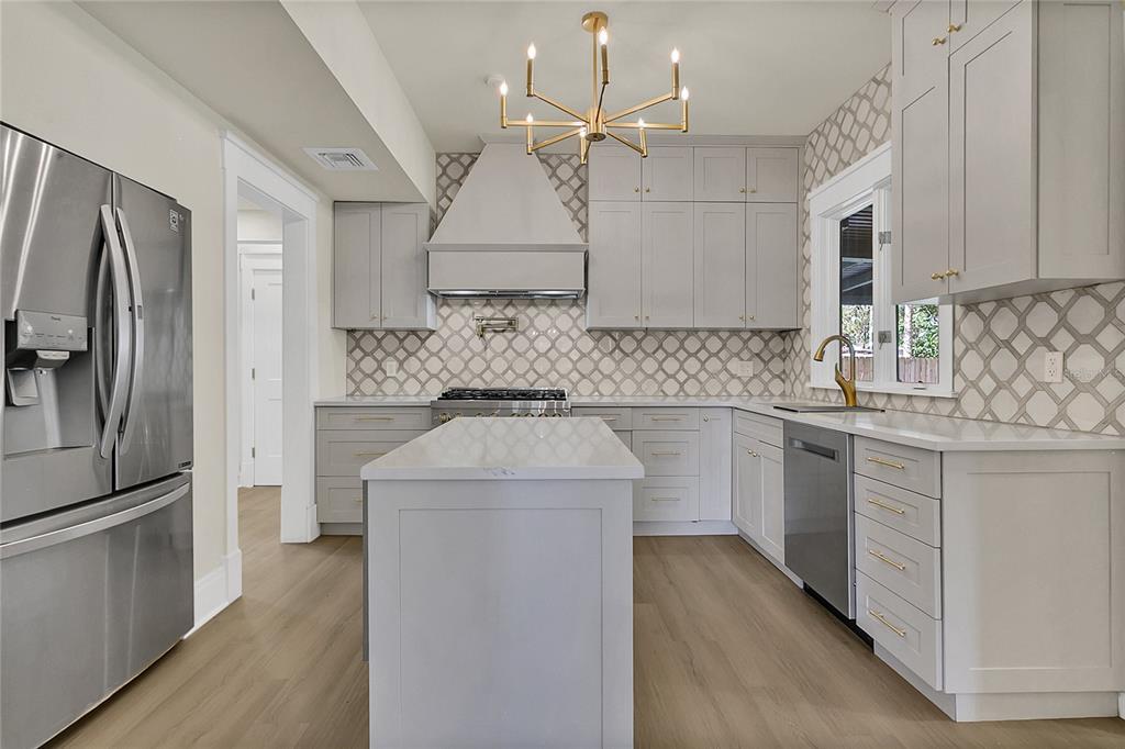 A modern kitchen features light gray cabinetry, a central island, and a patterned tile backsplash — 226 N ELLIOTT AVENUE, SANFORD, FL
