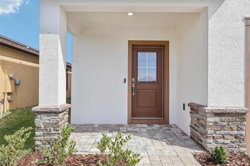 A brown front door with a glass window sits under a covered porch with stone — 3153 CUP DRIVE, LAKELAND, FL