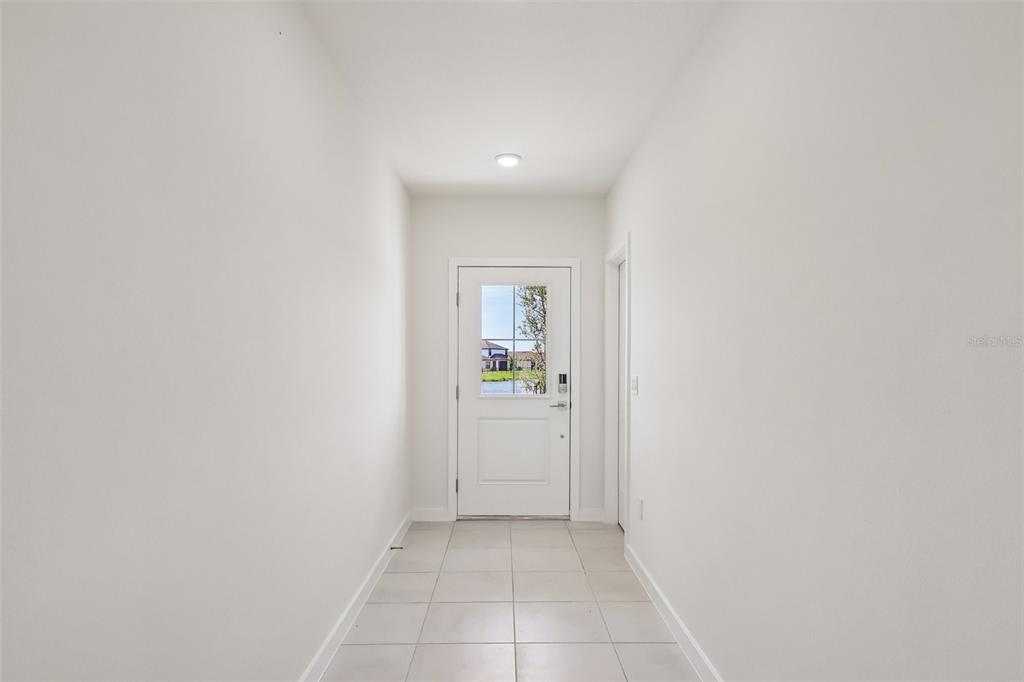 A bright entryway features white walls, light-colored tile flooring, and a door with a glass pane — 3153 CUP DRIVE, LAKELAND, FL