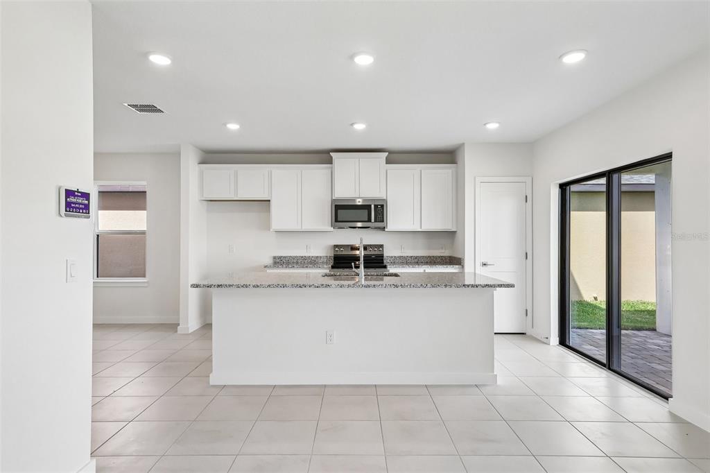 A modern kitchen features white cabinets, a central island, stainless steel appliances, and tile flooring — 3153 CUP DRIVE, LAKELAND, FL