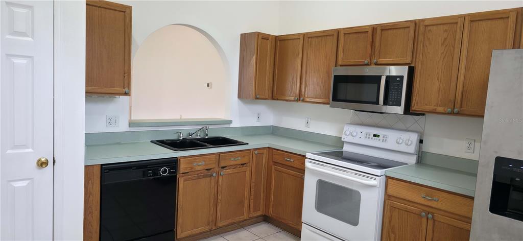 A kitchen features oak cabinets, green countertops, black appliances, and a white electric range — 2160 EOLA COURT, OVIEDO, FL