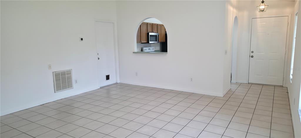 An interior view of a room with white walls, tiled floors, and an arched kitchen pass-through — 2160 EOLA COURT, OVIEDO, FL
