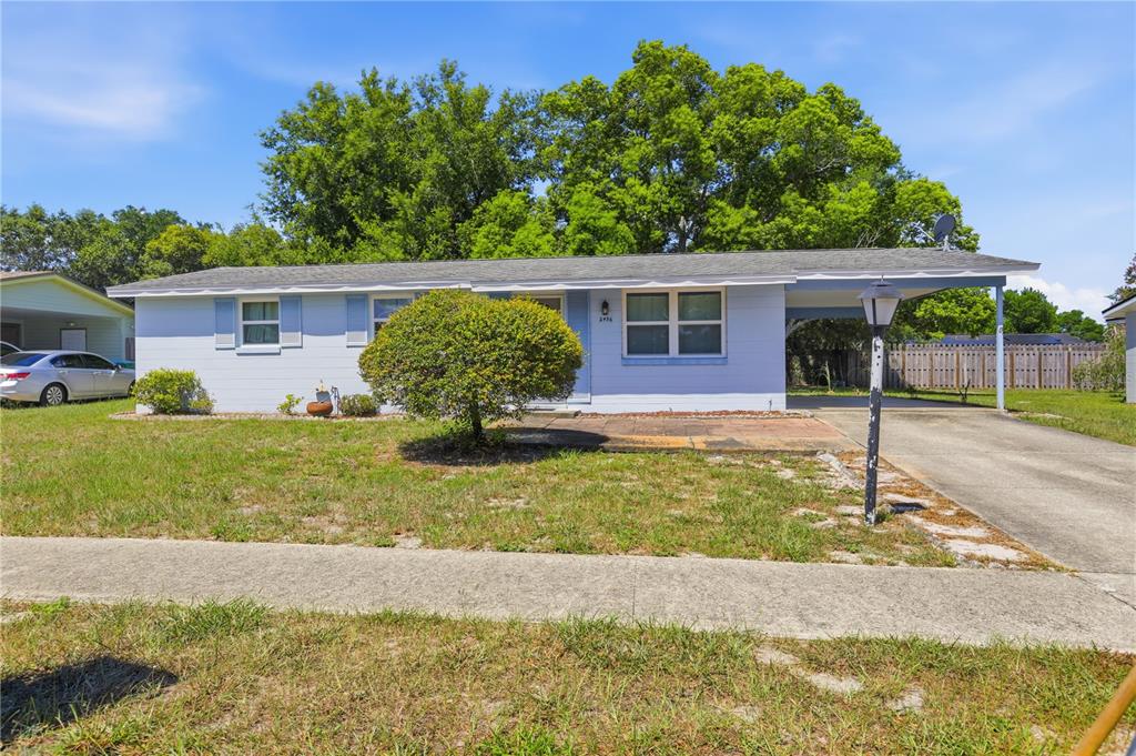 A light blue single-story house with a carport, a front lawn, and a concrete driveway — 2456 KIMBERLY DRIVE, DELTONA, FL
