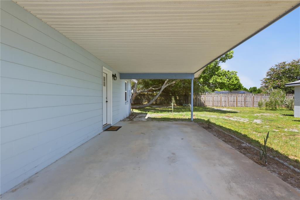 A concrete carport with a light blue exterior wall and a white door — 2456 KIMBERLY DRIVE, DELTONA, FL
