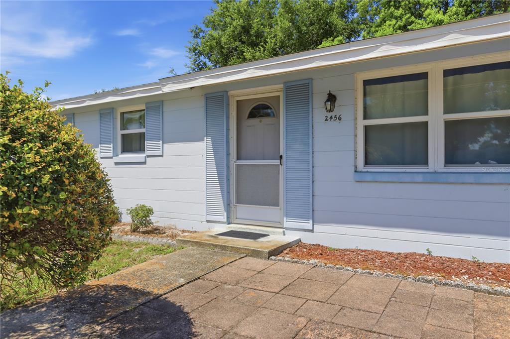 The exterior of a light blue house features a front door with shutters and windows — 2456 KIMBERLY DRIVE, DELTONA, FL