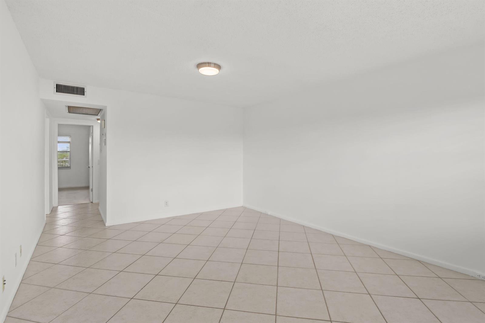 An empty room with white walls, a ceiling light fixture, and light-colored tiled flooring — 124 Preston C, Boca Raton FL 33434, BOCA RATON, FL