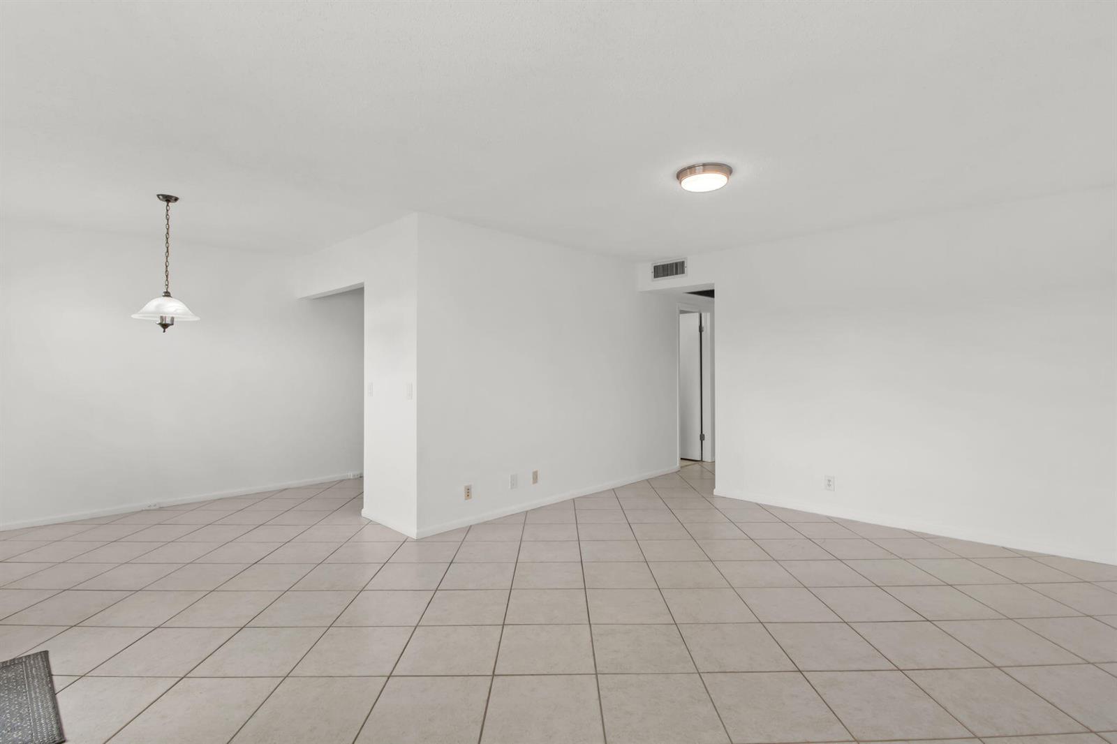 An empty room with white walls, a tiled floor, and a hanging pendant light — 124 Preston C, Boca Raton FL 33434, BOCA RATON, FL
