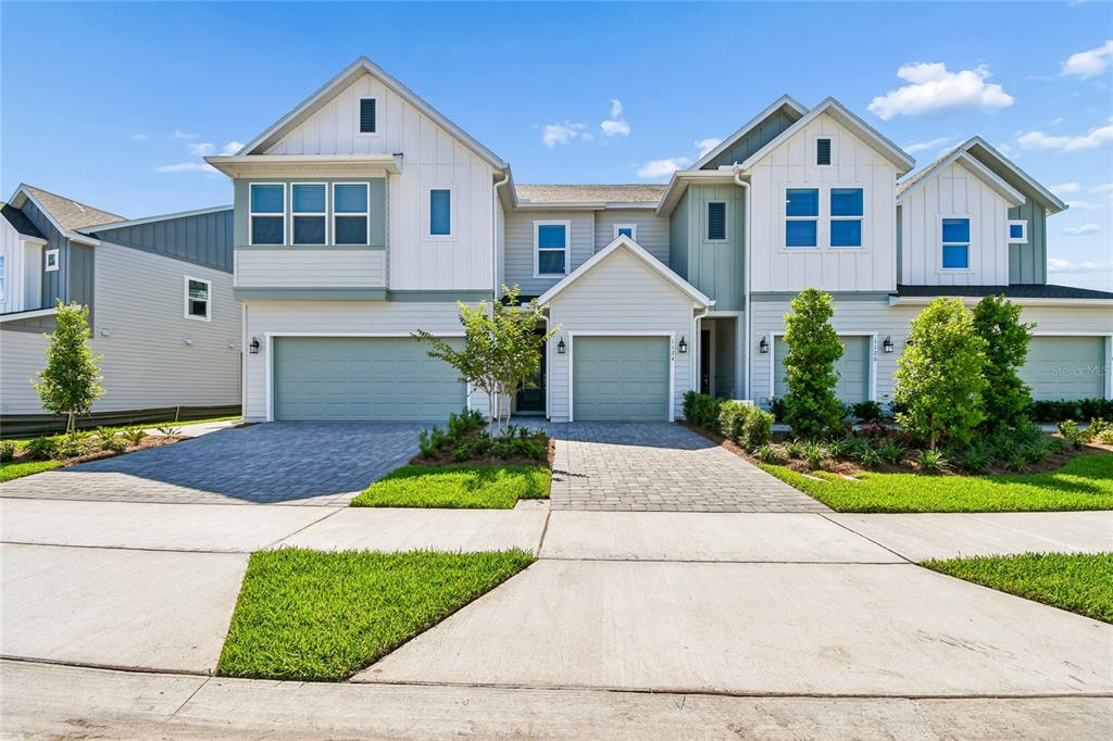 A two-story residential building with light-colored siding, multiple gables, and two attached garages — 1124 WILD CREST LANE, DAYTONA BEACH, FL