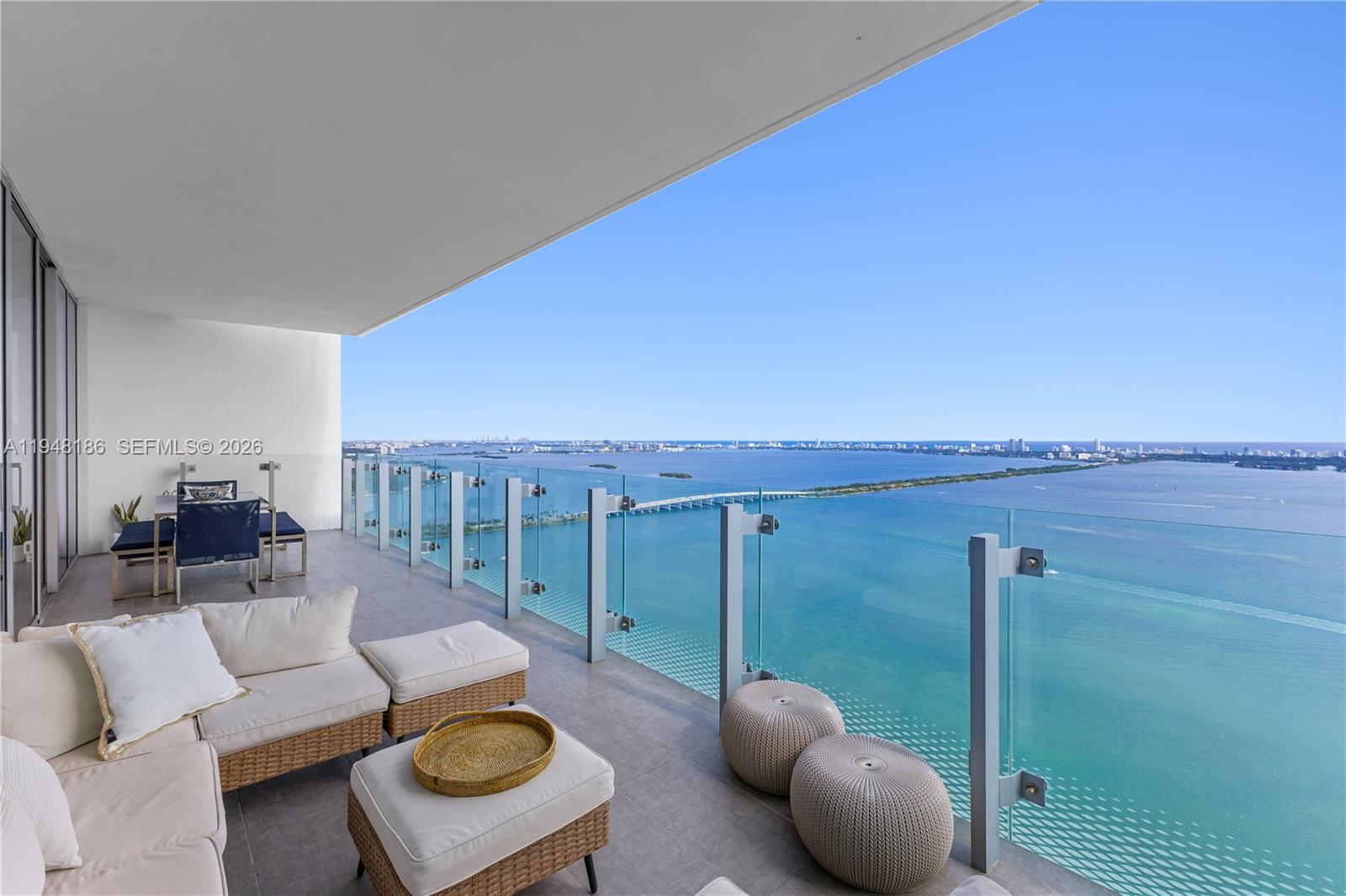 A spacious balcony features outdoor seating and a glass railing overlooking a large bay — 700 NE 26th Ter # 4701, Miami FL 33137, MIAMI, FL