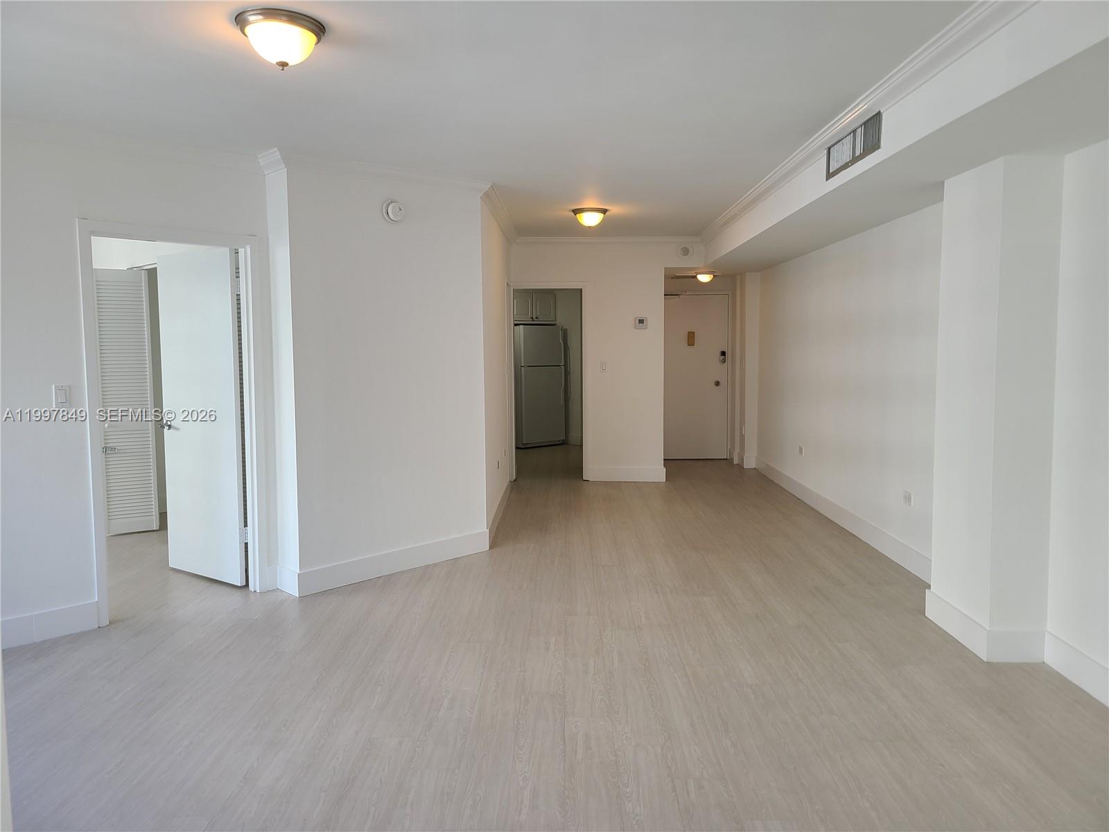 An empty room with light wood-look flooring, white walls, and two ceiling light fixtures — 999 Brickell Bay Dr # 1207, Miami FL 33131, MIAMI, FL