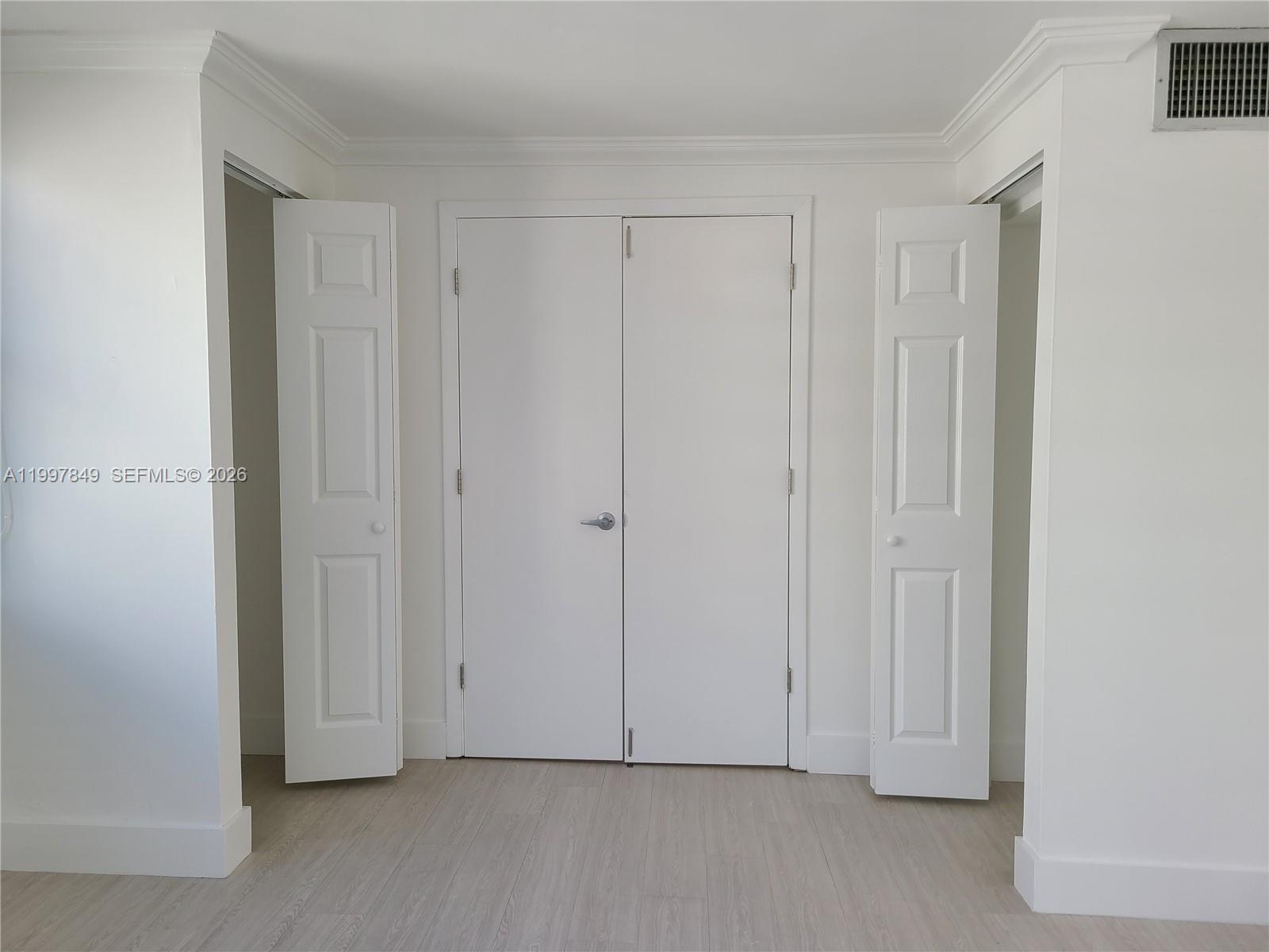 A room features light wood-look flooring, white walls, and three sets of white interior doors — 999 Brickell Bay Dr # 1207, Miami FL 33131, MIAMI, FL
