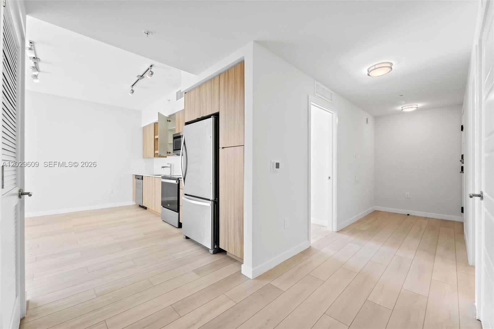 A modern kitchen features light wood cabinetry, stainless steel appliances, and light-colored wood flooring — FORT LAUDERDALE, FL