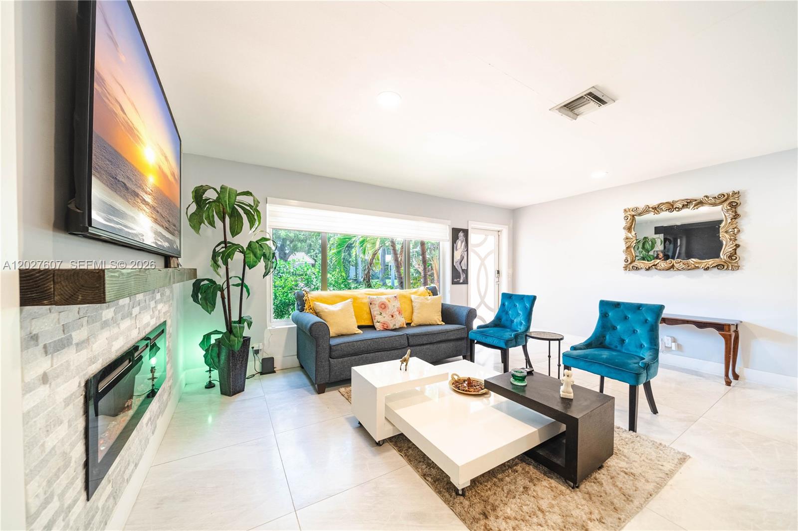 A living room features a fireplace, a grey sofa, two blue chairs, and white tables — 1101 NE 5th St, Hallandale Beach FL 33009, HALLANDALE BEACH, FL