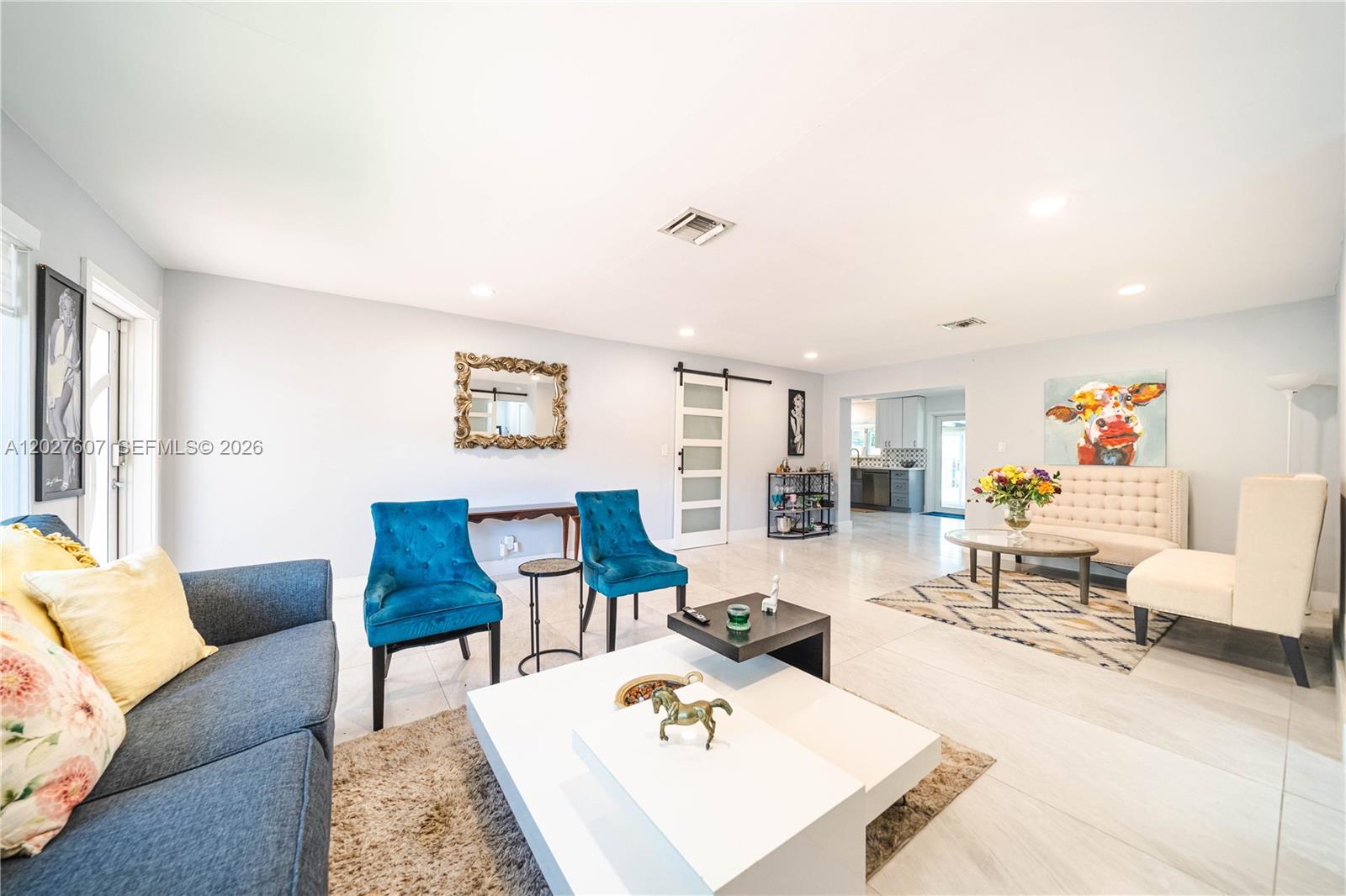 A spacious living room features blue accent chairs, a white coffee table, and tile flooring — 1101 NE 5th St, Hallandale Beach FL 33009, HALLANDALE BEACH, FL