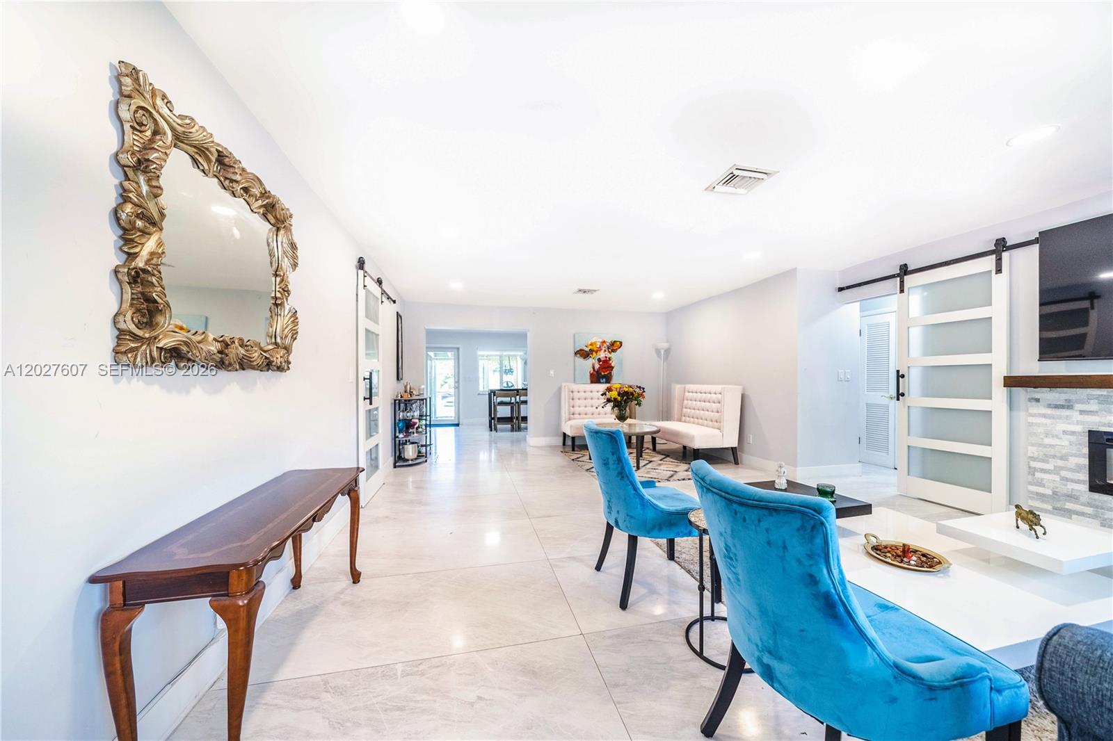 A living room features light tile floors, blue velvet chairs, and white sliding barn doors — 1101 NE 5th St, Hallandale Beach FL 33009, HALLANDALE BEACH, FL