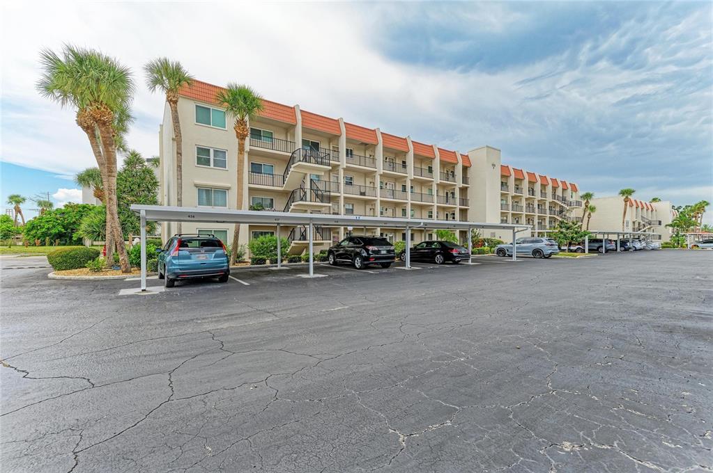 A multi-story apartment building with a covered parking area and palm trees in front — 220 SANTA MARIA STREET UNIT 338, VENICE, FL