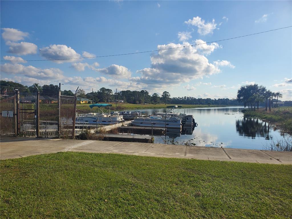 A concrete boat ramp leads to a dock with several pontoon boats on a lake — 715 INDIAN LAKE DRIVE, INDIAN LAKE ESTATES, FL