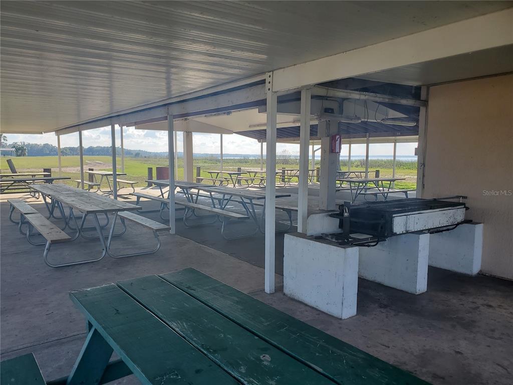 A covered outdoor pavilion features multiple picnic tables and a large built-in charcoal grill — 715 INDIAN LAKE DRIVE, INDIAN LAKE ESTATES, FL