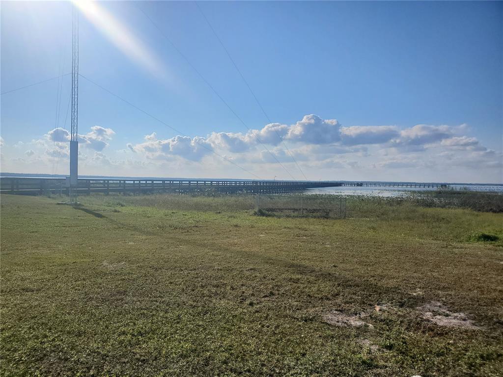 A long wooden pier stretches across a lake under a clear blue sky — 715 INDIAN LAKE DRIVE, INDIAN LAKE ESTATES, FL