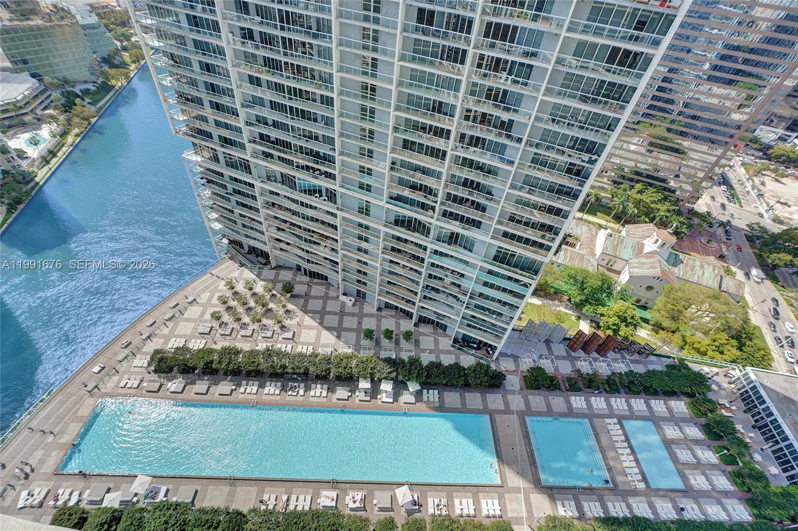 An aerial view shows a high-rise building with a large pool deck and river — 475 Brickell Ave # 5010, Miami FL 33131, MIAMI, FL