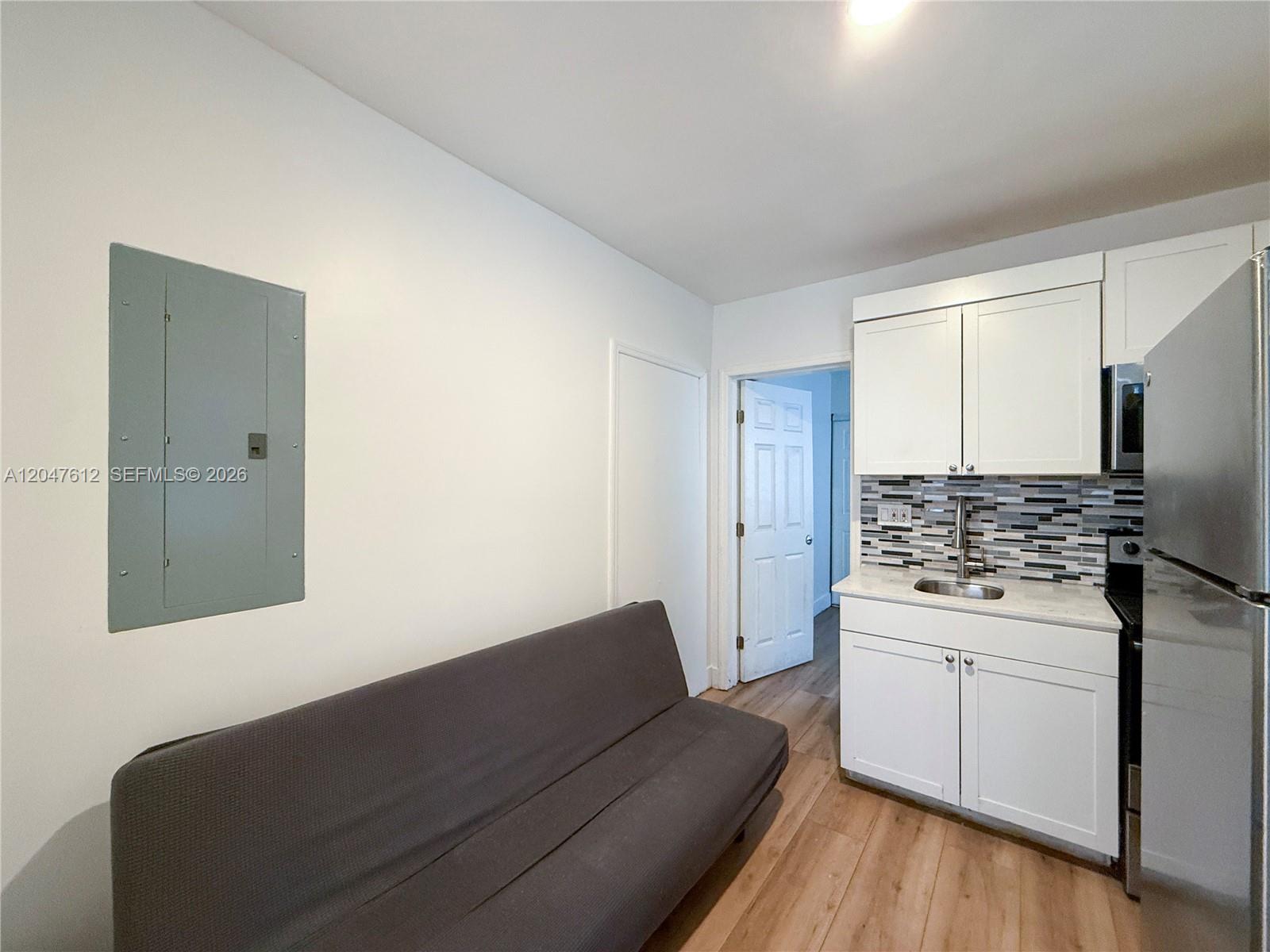A small kitchen area features white cabinets, a stainless steel refrigerator, and a gray futon — 2 SW 6th Ave # 4, Dania Beach FL 33004, DANIA BEACH, FL