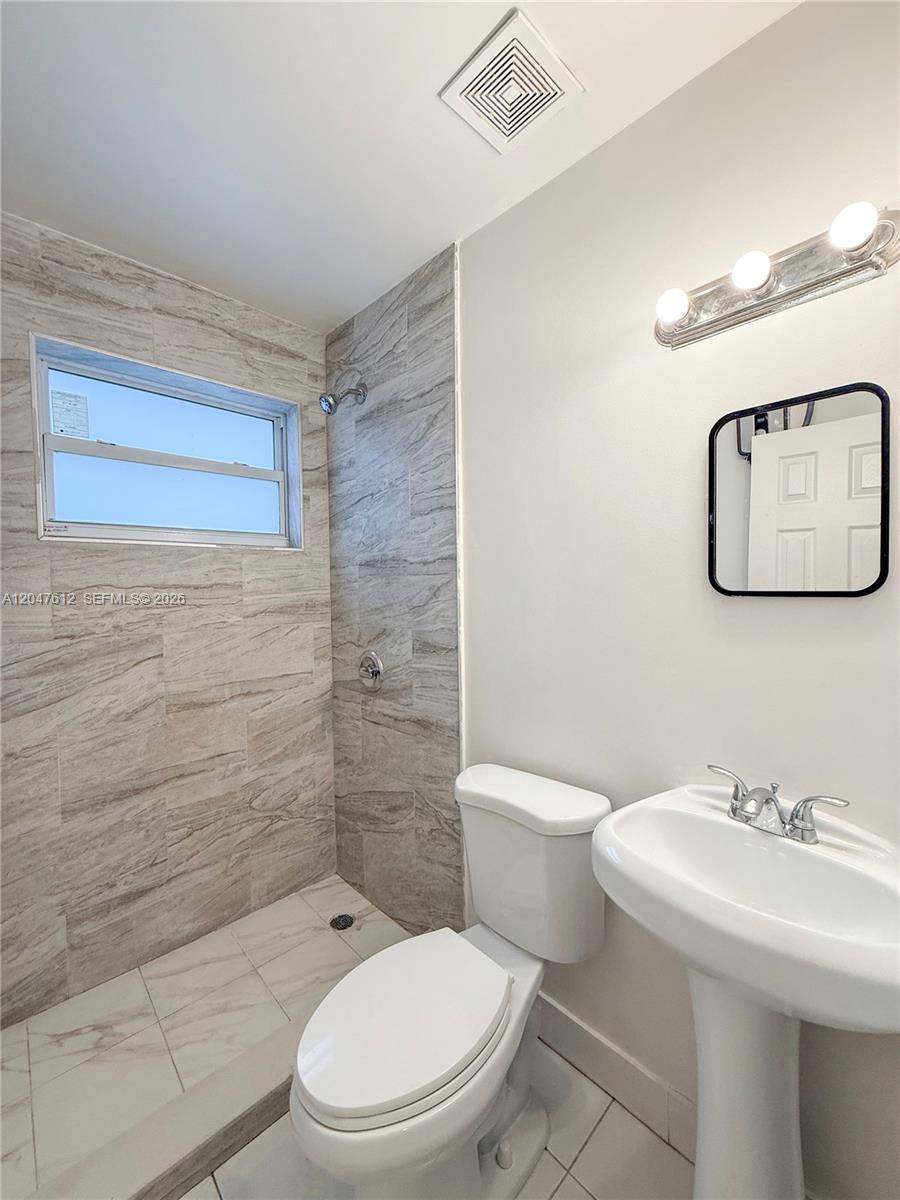 A bathroom features a walk-in shower with tiled walls, a pedestal sink, and a toilet — 2 SW 6th Ave # 4, Dania Beach FL 33004, DANIA BEACH, FL