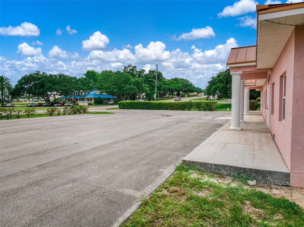 A pink building with white columns overlooks a large asphalt parking lot under a sky — 401 W INTERLAKE BOULEVARD, LAKE PLACID, FL