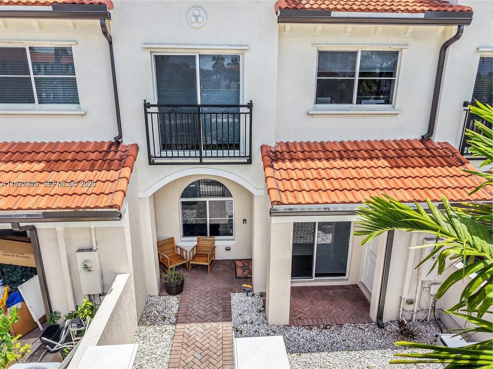 An exterior view of a two-story townhouse with a brick walkway and a small balcony — LAUDERDALE LAKES, FL