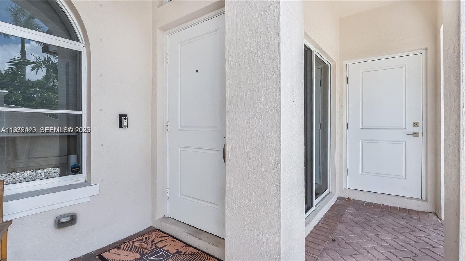 An exterior entryway features a white front door, a side door, and a arched window — LAUDERDALE LAKES, FL