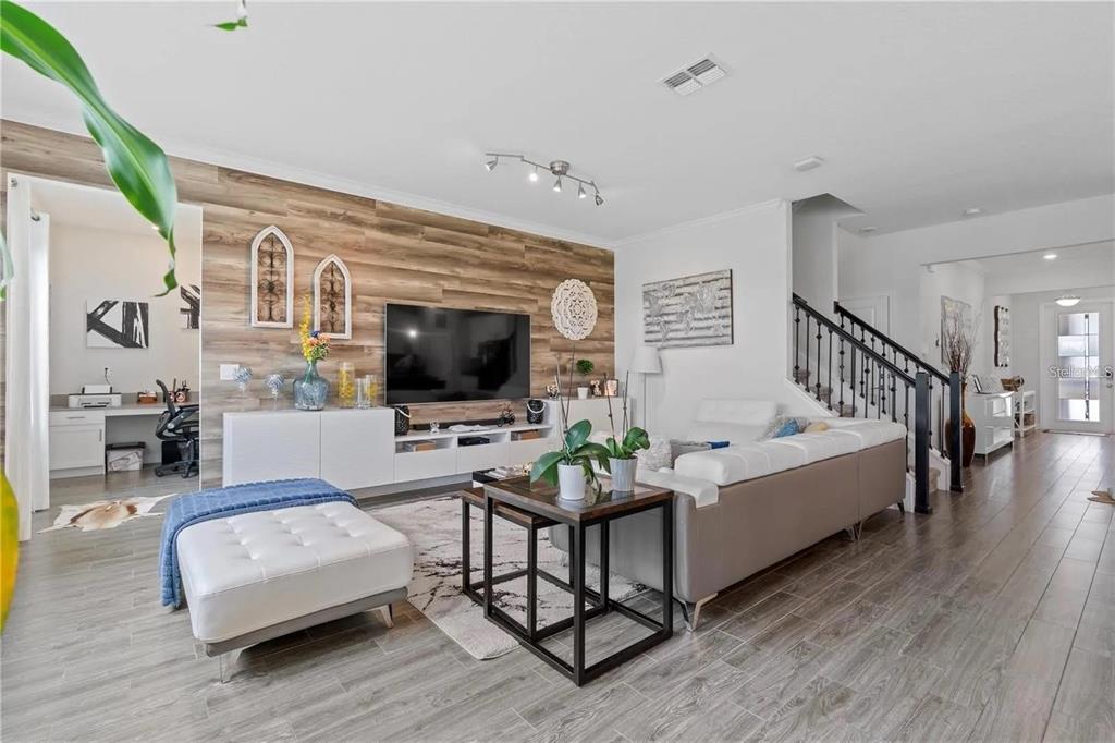 A living room features a wood-paneled accent wall, a white sectional sofa, and tile flooring — 11819 IMAGINARY WAY, ORLANDO, FL