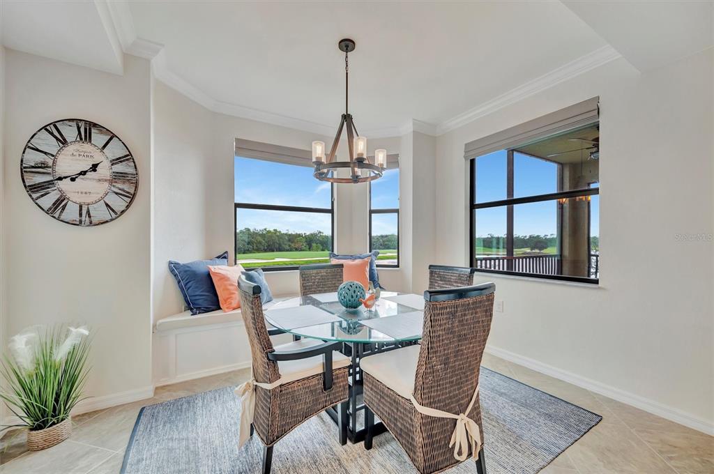 A dining area features a glass-topped table, wicker chairs, a window seat, and a chandelier — 17118 VARDON TERRACE UNIT 207, BRADENTON, FL