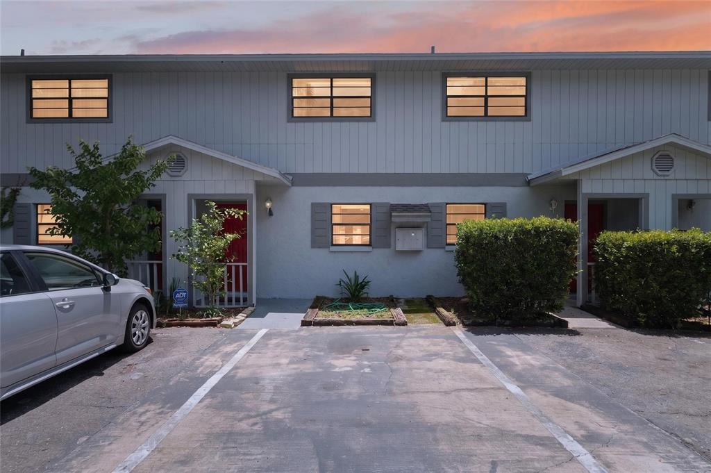 A two-story townhouse exterior features a paved parking space, red front doors, and landscaping — 4123 SW 15TH PLACE UNIT 2, GAINESVILLE, FL