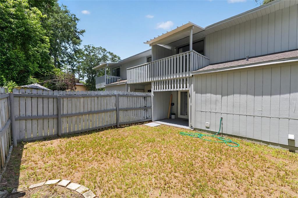 A fenced backyard features a patch of grass and a two-story building with balconies — 4123 SW 15TH PLACE UNIT 2, GAINESVILLE, FL