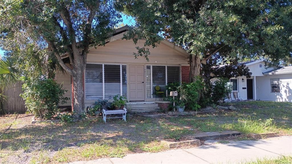 A single-story house with a beige exterior, louvered windows, and a front porch under trees — 4428 4TH AVE S, ST PETERSBURG, FL